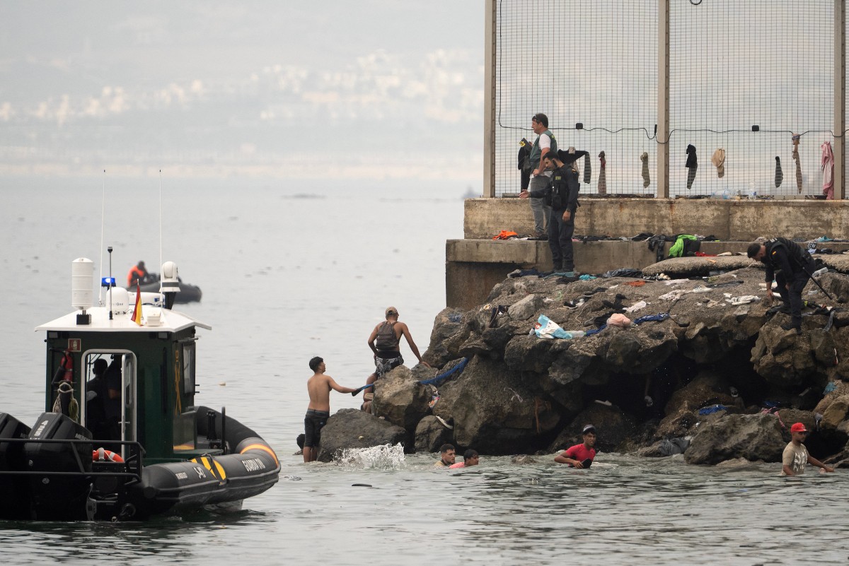 Agentes de la Guardia Civil de España vigilan la zona mientras migrantes intentan entrar en el enclave de Ceuta